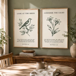 May include: Two rectangular wall art prints in light wood frames. The left print features a bird illustration with the text LOOK AT THE BIRDS and Matthew 6:26. The right print features a lily illustration with the text CONSIDER THE LILIES and Matthew 6:28.
