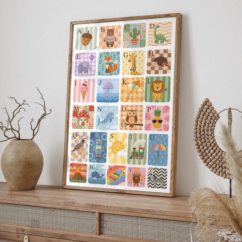 May include: A framed alphabet poster featuring colorful illustrations for each letter. The artwork includes images of an acorn, bear, cactus, dinosaur, elephant, fox, giraffe, hedgehog, ice cream, jellyfish, kite, lion, mushroom, whale, owl, pineapple, quail, robot, sun, train, umbrella, volcano, whale, rainbow, yak, and zebra.