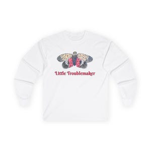 May include: White long-sleeve shirt featuring a colorful illustration of a spotted insect with red and black accents. The text "Little Troublemaker" is printed in a cursive font below the insect graphic.
