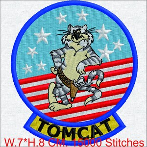 Pode incluir: Um emblema bordado circular apresentando um personagem de gato cinza tigrado usando um coldre contra um fundo azul claro com estrelas brancas e listras horizontais vermelhas e brancas. Uma faixa amarela na parte inferior exibe o texto TOMCAT.