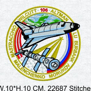 Puede incluir: Parche bordado con un diseño de transbordador espacial y estación espacial dentro de un borde circular dorado. El diseño incluye texto y un patrón de estrella, de 10 cm por 10 cm.