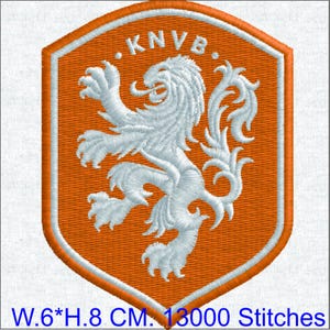 May include: An orange shield-shaped embroidered patch featuring a white rampant lion and the text KNVB at the top. The patch measures 6 cm in width and 8 cm in height, with a total stitch count of 13000 stitches visible in the design.
