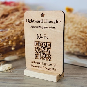 May include: A wooden WiFi sign with the text "Lightward Thoughts" and "Illuminating your ideas." The sign includes a QR code and the network and password details. The sign is made of light-colored wood and has a star at the top.