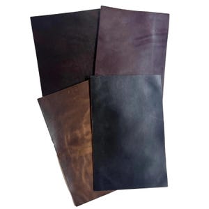 May include: A collection of leather sheets in various shades of brown, black, and purple. The sheets are rectangular and appear to be of different sizes. The leather has a natural, textured appearance, with variations in color and tone.