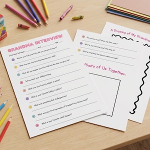 Op de afbeelding: Afdrukbare interviewvellen voor een oma, met vragen en ruimte voor antwoorden. De vellen zijn omringd door kleurpotloden, waskrijtjes en een pakje sap, wat duidt op een leuke activiteit voor kinderen. De tekst "GRANDMA INTERVIEW" is zichtbaar.