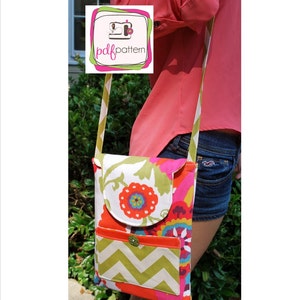 Puede incluir: Un bolso bandolera de tela colorido con un patrón de chevron y una solapa floral. El bolso tiene una cremallera y una correa larga ajustable. El bolso lo lleva una persona con una camisa rosa y pantalones cortos de mezclilla.