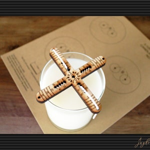 May include: A wooden candle making tool with markings for measuring candle diameter. The tool is placed on top of a glass jar filled with white wax.