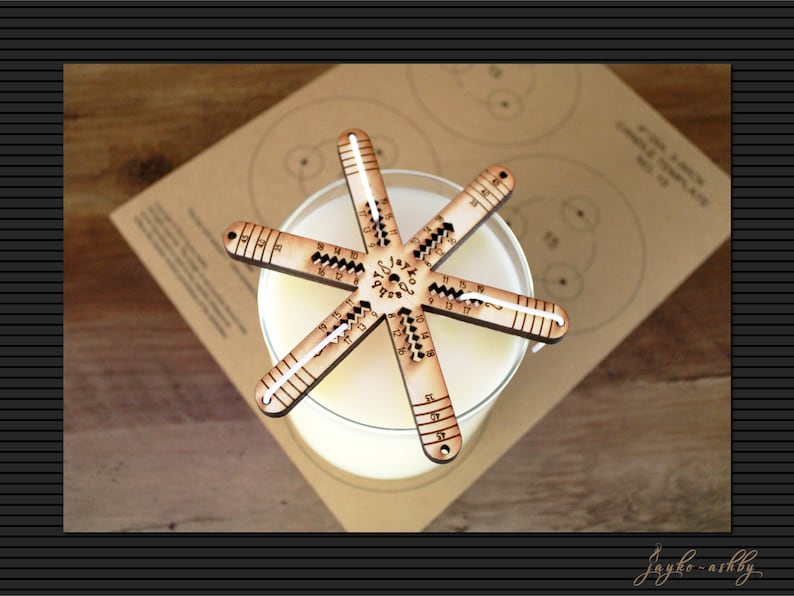 May include: A wooden candle making tool with a star shape and markings for measuring. The tool is on top of a glass jar with a white candle inside.