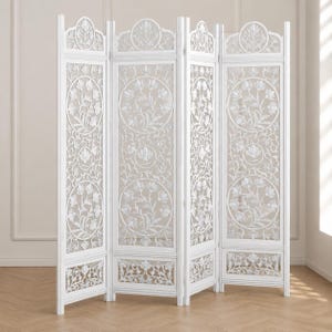 May include: A white, four-panel room divider with intricate floral carvings. The screen features detailed botanical patterns within oval and rectangular frames, creating an elegant and airy design. The divider stands on a light-colored wooden floor.