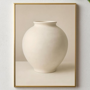 Puede incluir: Una impresión enmarcada con un jarrón esférico de color crema. El jarrón tiene un cuerpo ancho y redondeado y un cuello estrecho. La impresión está sobre un fondo neutro y enmarcada en un marco dorado. La estética general es minimalista y moderna.
