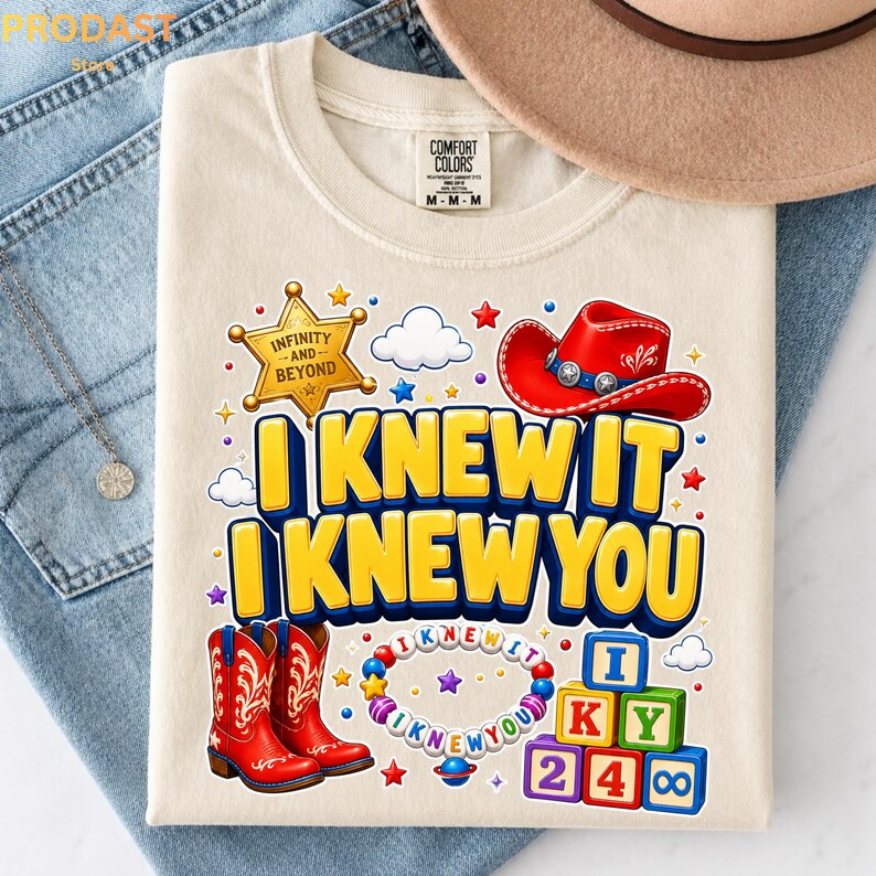 May include: A cream-colored t-shirt featuring a graphic print with a red cowboy hat, a gold sheriff star labeled "INFINITY AND BEYOND," red cowboy boots, a beaded bracelet with text, and colorful alphabet blocks spelling "I KNEW IT I KNEW YOU."