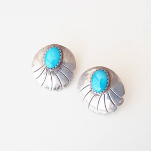 May include: A pair of silver earrings with turquoise stones set in a scalloped design.