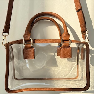 Clear stadium-approved handbag in brown trim shown close-up, featuring premium anti-scratch PVC and structured handles