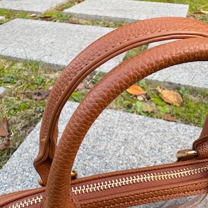 Detailed view of double top handles on a brown-trim clear PVC stadium bag.