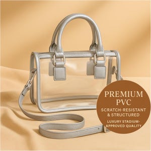 Puede incluir: Un bolso transparente de PVC con marco, asas y correa para el hombro plateados. El bolso tiene un diseño estructurado y herrajes plateados. La imagen incluye un círculo marrón con el texto "PREMIUM PVC, SCRATCH-RESISTANT & STRUCTURED, LUXURY STADIUM-APPROVED QUALITY."
