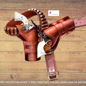 Può includere: Un set di fondine per pistole in pelle marrone con cintura e bandoliera. Il set include due revolver con manici bianchi e diversi proiettili. Il set è esposto su una superficie di legno.