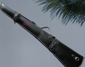 Könnte beinhalten: Ein schwarzes Billard-Queue-Etui aus Leder mit weißen Kontrastnähten, zwei verstellbaren Schnallenriemen, einem Tragegriff und einem silbernen D-Ring an der Basis. Die Buchstaben EBP sind in Pink auf dem oberen Teil des zylindrischen Etuis gedruckt.
