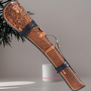 May include: A brown leather quiver with detailed floral and geometric designs. It features a black leather strap and a gold-coloured metal ring. The text "E-Beautiful People" is visible on the bottom right.