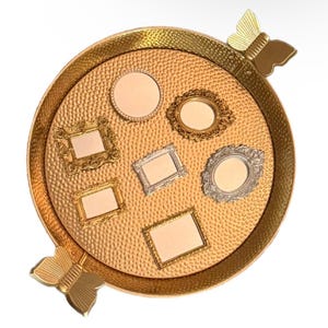 May include: A gold-colored, round tray with a textured surface and butterfly-shaped handles. The tray holds several small, ornate picture frames in gold and silver, with various shapes and designs. The frames are empty.