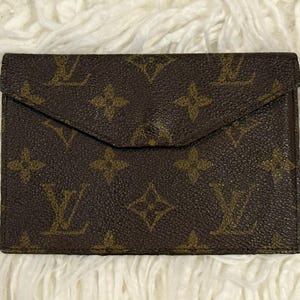 Könnte beinhalten: Braunes Lederportemonnaie mit Klappenverschluss. Das Portemonnaie hat ein sich wiederholendes Muster aus ineinandergreifenden "LV"-Monogrammen und floralen Motiven in hellerer Brauntönung. Das Portemonnaie ist rechteckig und scheint neu zu sein.