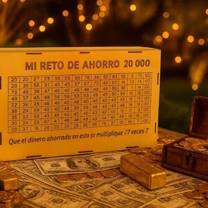 Puede incluir: Una caja de madera con un desafío de ahorro impreso, un pequeño cofre del tesoro lleno de monedas y una barra de oro se exhiben sobre una superficie cubierta de billetes y monedas. La caja dice "MI RETO DE AHORRO 20 000".