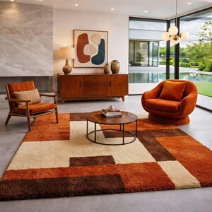 Puede incluir: Una alfombra rectangular con un patrón geométrico de grandes bloques en tonos naranja quemado, marrón oscuro y crema. La alfombra tiene un pelo grueso y texturizado, situada en una habitación con un aparador de madera, dos sillones y una mesa.