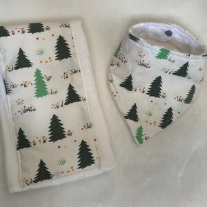 May include: A white burp cloth and bib with a green, white, and red pattern of trees and flowers.