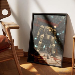 以下が含まれることがあります： 格納庫にいる大きなロボットを描いた額入りのアートワーク。ロボットはベージュとグレーを基調とし、下に数体の人物が立っています。アートワークは黒いフレームに入っており、壁に立てかけられています。