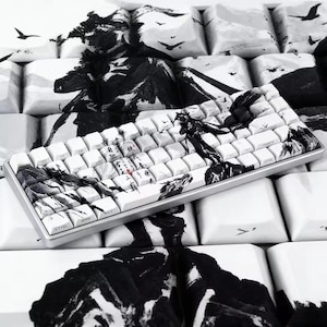 Puede incluir: Un teclado mecánico con teclas blancas que presentan un diseño de pintura a tinta negra. Las teclas muestran paisajes montañosos, aves en vuelo y columnas verticales de caligrafía china negra con pequeños detalles en color rojo.