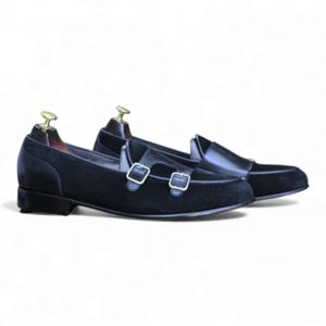 Pair of black two-tone slip-on dress shoes with silver buckles.
