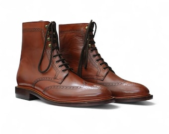 May include: A pair of brown leather boots with a classic brogue design. The boots have a lace-up closure, a rounded toe, and a sturdy sole. The leather has a polished finish, and the boots are set against a white background.