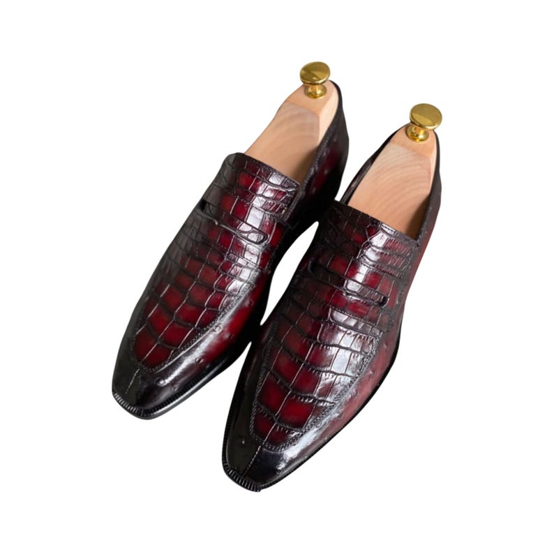 Men's wine burgundy loafers with alligator crocodile print leather and gold metal keeper bar. Handcrafted luxury dress shoes with elegant silhouette. Ideal for weddings, business professional, executive style, or distinguished occasions. Sizes 6-15.