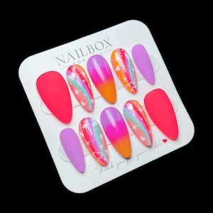 May include: A set of ten artificial nails in various colors and designs. The nails include solid matte red and purple, and others with rainbow and heart designs. The text "NAILBOX FOR U" is visible on the card. The card also includes the text "Thank you for your order."