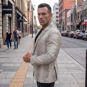 May include: A tailored blazer featuring a light grey and white snakeskin pattern with a notched lapel, long sleeves, and a single-breasted front closure. The garment is constructed with a structured fit, visible side vents, and two front pockets.