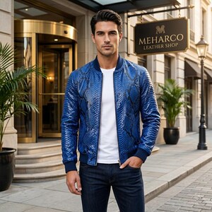May include: A vibrant blue bomber jacket featuring a detailed snakeskin texture pattern, a solid white crew neck t-shirt, and dark blue denim jeans. The jacket has a ribbed collar, cuffs, and hem, with a full-length front zipper closure.