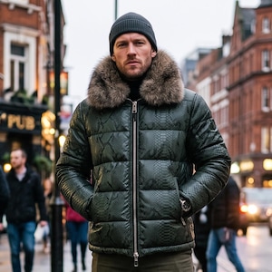 May include: A dark green puffer jacket with a snakeskin-like texture, a full-length silver zip, and a thick, fluffy brown faux fur collar. The jacket is worn with a dark grey knit beanie and a black turtleneck jumper underneath.