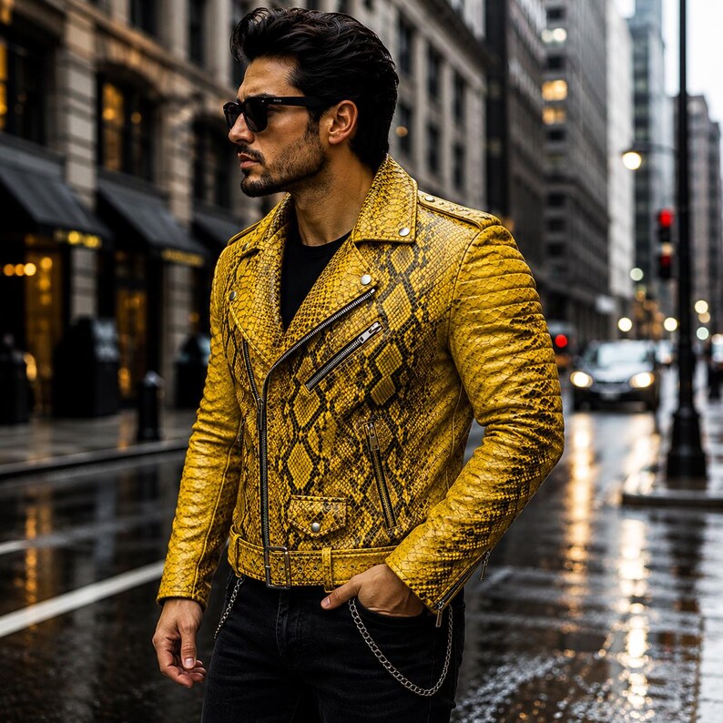 May include: A yellow motorcycle jacket with a snakeskin pattern, featuring a notched lapel, silver-tone metal zippers, a front flap pocket with a snap button, and an adjustable waist belt with a buckle, worn over a plain black shirt.