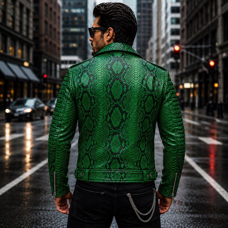 K&ouml;nnte beinhalten: Eine leuchtend gr&uuml;ne Motorradjacke mit einem detaillierten schwarzen Schlangenledermuster, einem breiten Kragen und gesteppten Schulterpartien. Die Jacke verf&uuml;gt &uuml;ber silberfarbene Metallrei&szlig;verschl&uuml;sse an den &Auml;rmeln und einen passenden G&uuml;rtel.
