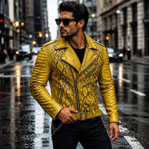 May include: A bright yellow motorcycle jacket featuring a textured snakeskin pattern, silver-toned metal zippers, snap button lapels, and an adjustable waist belt with a buckle. The jacket is worn over a plain black shirt with black trousers.