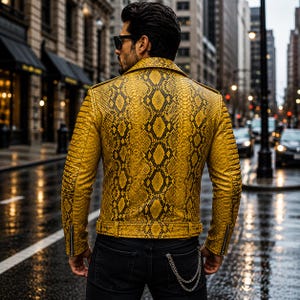 May include: A yellow and black snakeskin-patterned leather jacket with a wide collar, long sleeves featuring ribbed detailing on the shoulders, zippered cuffs, and a buckled waist belt, worn over dark denim jeans with a silver chain accessory.