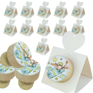Può includere: Tappi per bottiglie in legno e piccole scatole regalo. I tappi presentano un design circolare con un'illustrazione a cartoni animati di un ragazzo su un aereo. Le scatole regalo hanno una parte superiore a forma di cuore e un design circolare abbinato.