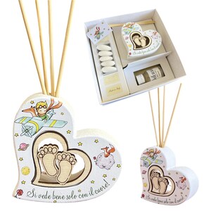 Può includere: Diffusore d'aria a forma di cuore a tema Piccolo Principe. Il diffusore in ceramica bianca presenta un ritaglio di impronte di bambino e illustrazioni del Piccolo Principe, una volpe e pianeti. È visibile anche il testo "Si vede bene solo con il cuore!"