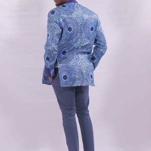 Puede incluir: Una chaqueta azul con un dise&ntilde;o estampado blanco y azul. La chaqueta tiene un cuello mandar&iacute;n y mangas largas. La persona lleva pantalones azules y zapatos marrones.