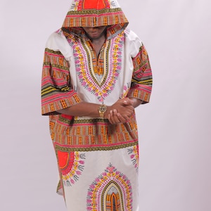 May include: A white hooded tunic with a colorful African print design. The tunic has a V-neck and long sleeves. The print features geometric shapes, circles, and lines in shades of red, orange, yellow, green, and pink.