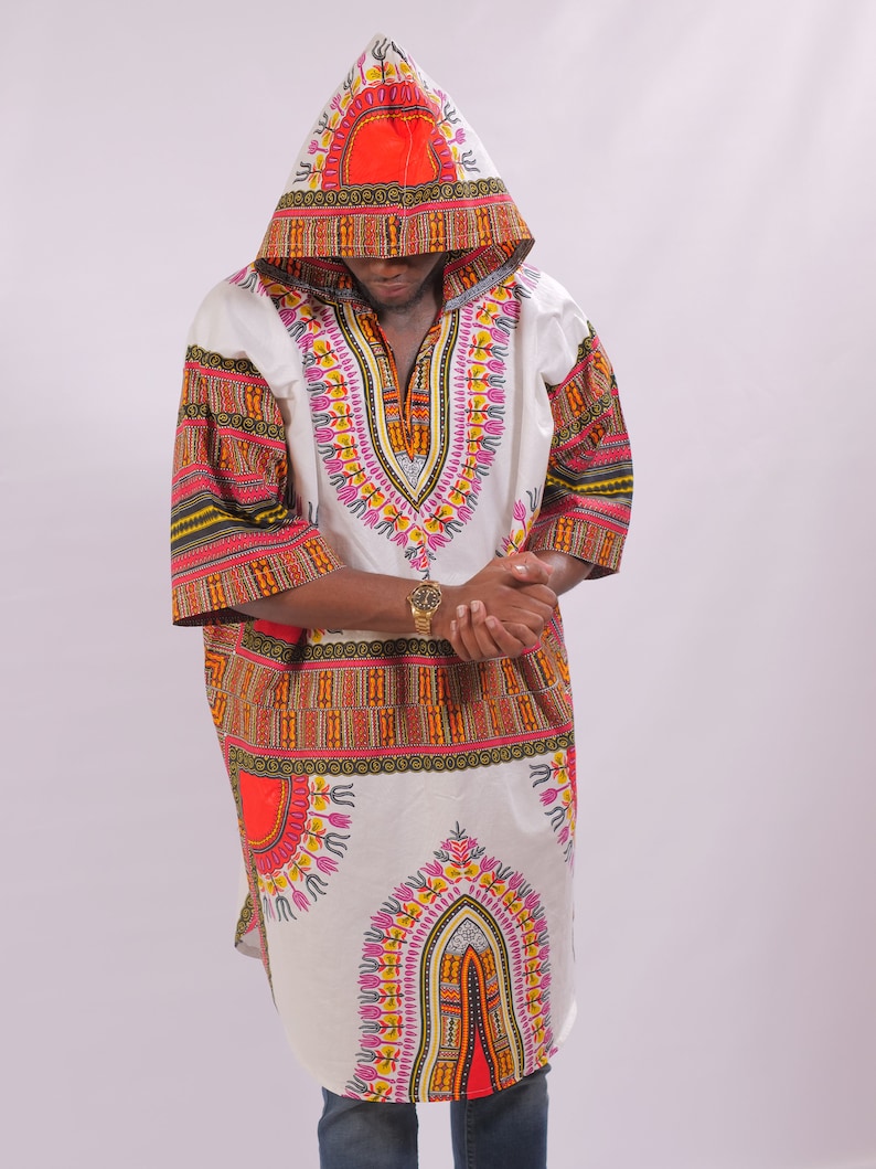 May include: A white hooded tunic with a colorful African print design. The tunic has a V-neck and long sleeves. The print features geometric shapes, circles, and lines in shades of red, orange, yellow, green, and pink.