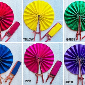 May include: Six hand fans in different colors: red, yellow, green, blue, pink, and purple. Each fan is made of fabric and has a wooden handle. The fans are arranged in two rows of three.
