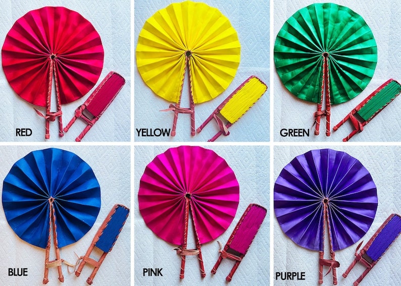 May include: Six hand fans in different colors: red, yellow, green, blue, pink, and purple. Each fan is made of fabric and has a wooden handle. The fans are arranged in two rows of three.