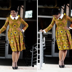 May include: A woman wearing a yellow and blue patterned dress with a white collar and long sleeves. She is standing on a set of stairs with a railing.