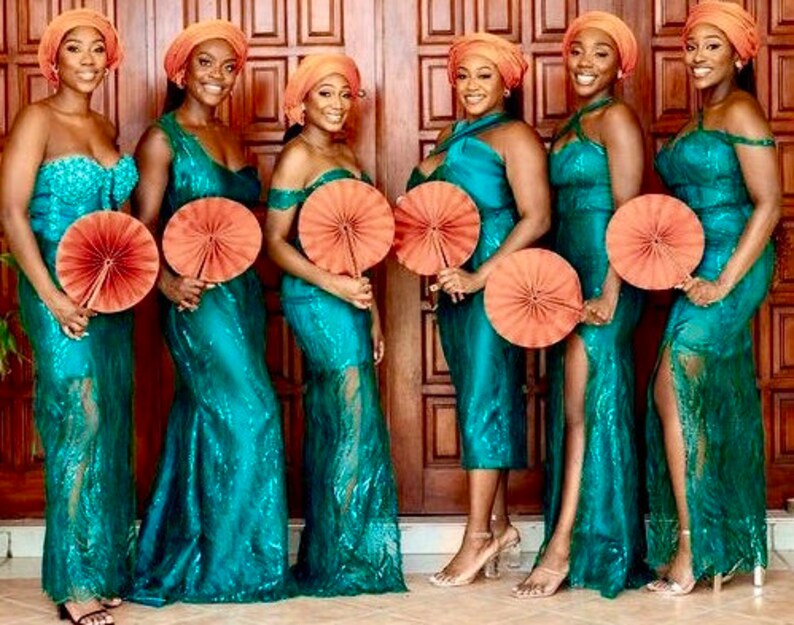 May include: Six bridesmaids wearing teal sequined dresses with orange headbands and holding orange hand fans.
