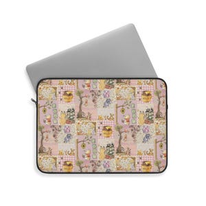 Puede incluir: Funda para portátil con un diseño de patchwork con personajes de Winnie the Pooh, tarros de miel y árboles sobre un fondo rosa. La funda tiene una cremallera negra y está diseñada para un portátil.